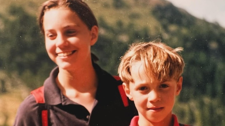 A young Kate Middleton smiling behind a young James Middleton