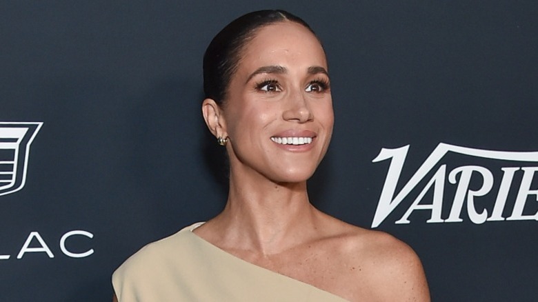 Meghan Markle smiling on the red carpet in a one-shoulder dress (2023)