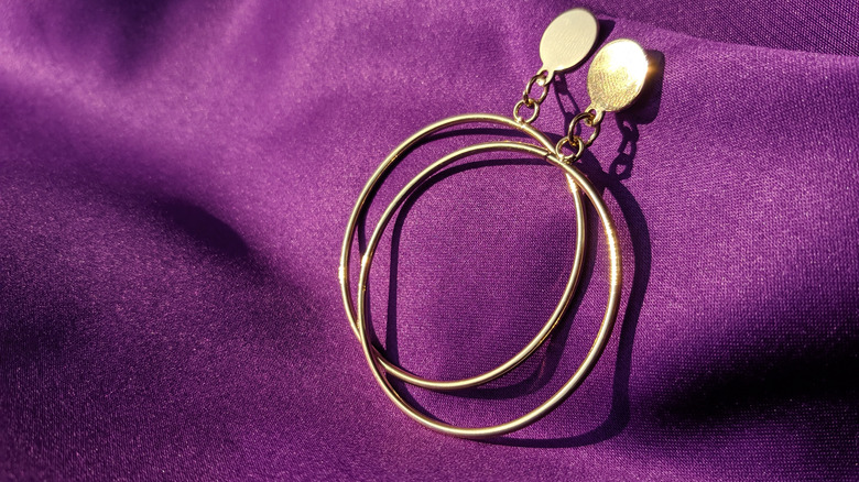 Gold hoop earrings on purple cloth
