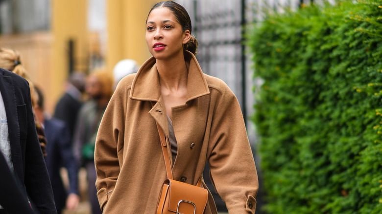 Women in a camel trench coat and tan bag