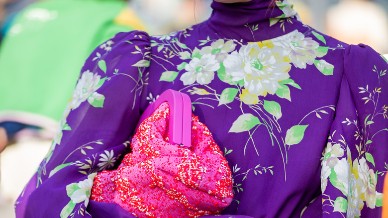 A purple floral dress with a hot pink bag