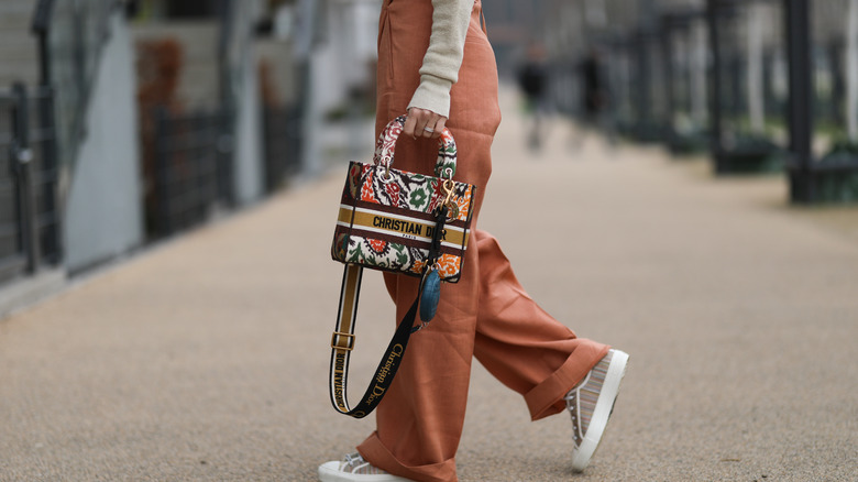 Rust pants with a Dior bag