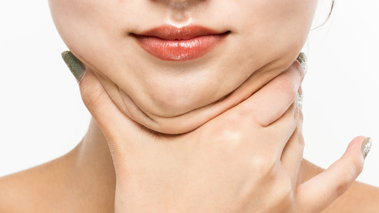 Woman with long sparkly fingernails holding her double chin.