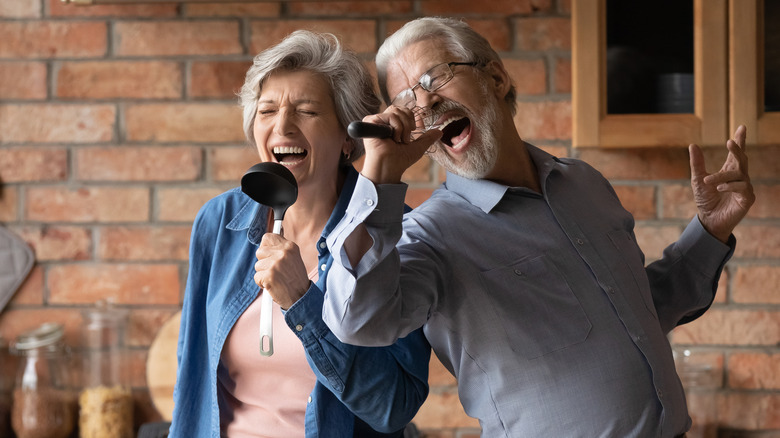 Elderly couple singing with kitchen utensils