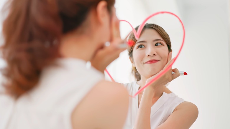 Woman draws heart on mirror with lipstick 