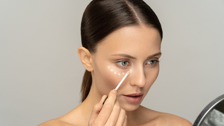 A woman applying concealer on her face