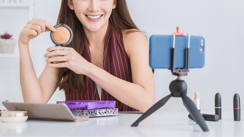 woman doing makeup on camera