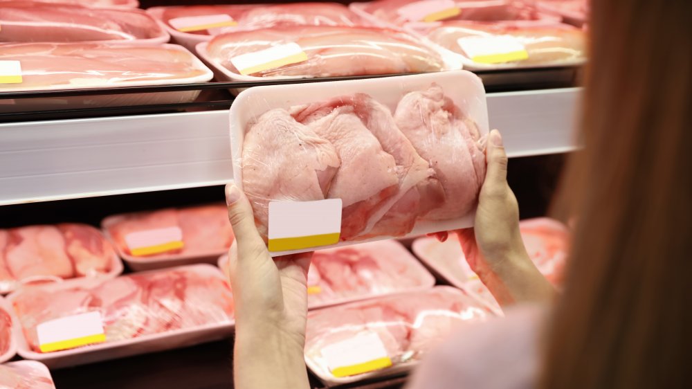 Woman buying chicken in grocery store