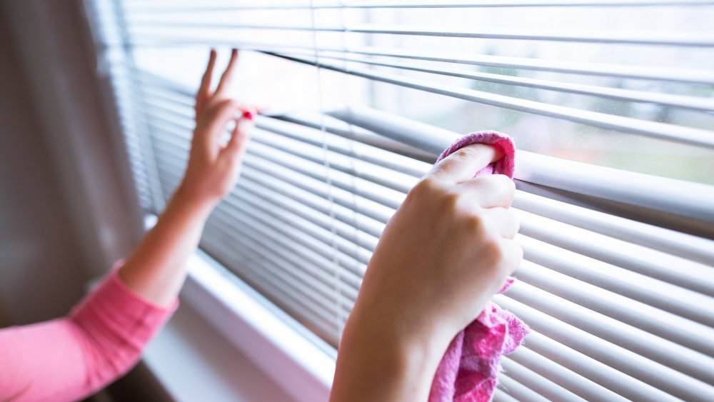 Woman cleaning blinds