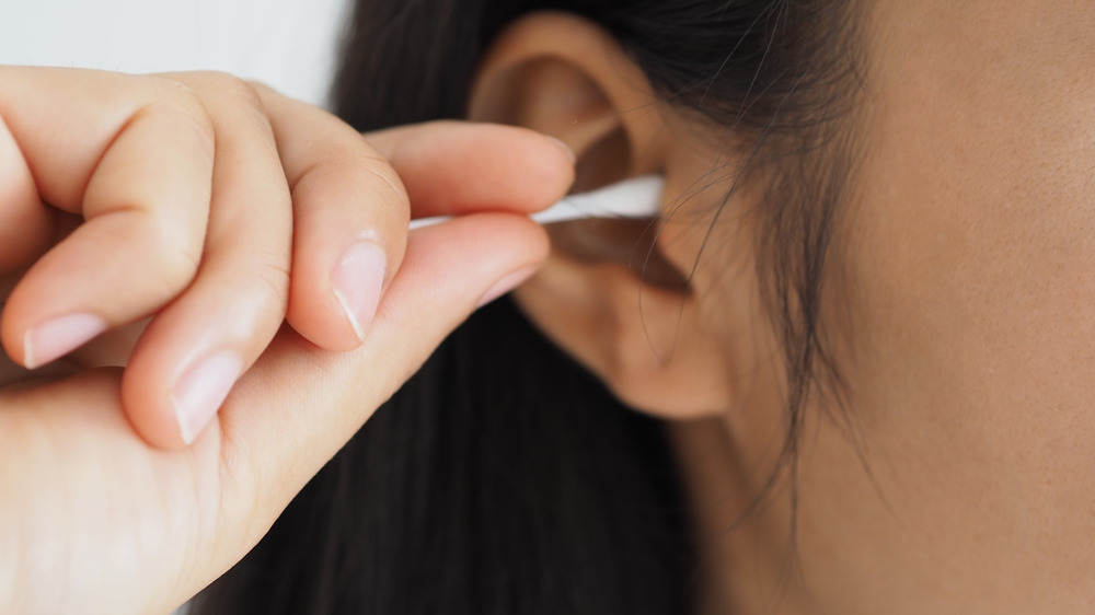 Woman cleaning her ear with a Q-tip