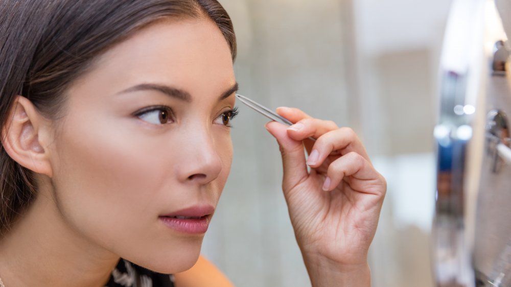 Woman plucking her eyebrows