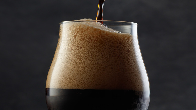 Dark beer pouring in a glass lots of foam