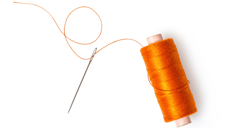 Orange thread and sewing needle