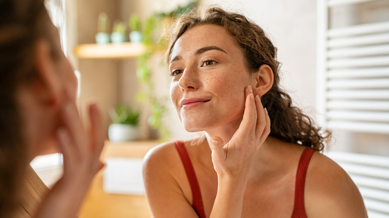 Woman checking her face in the mirror