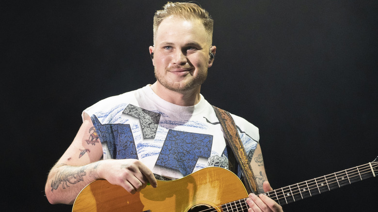 Zach Bryan playing guitar on stage