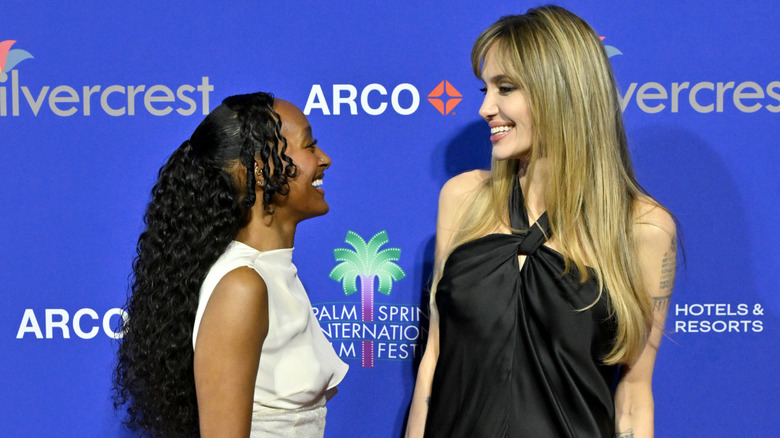 Zahara Jolie looks at Angelina Jolie on a red carpet, both smiling