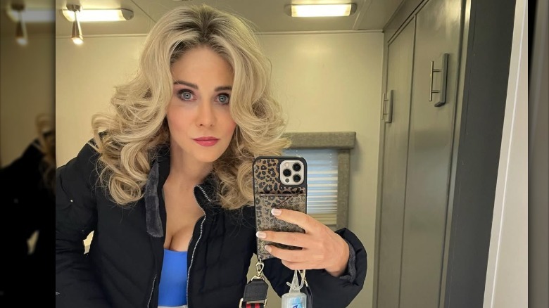 A blond Zooey Deschanel takes a selfie on set