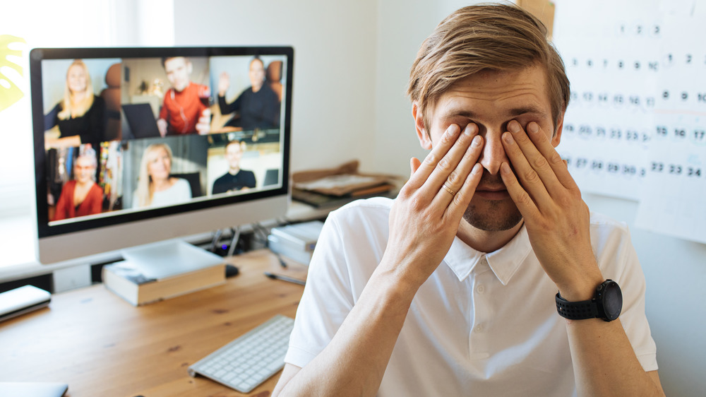 Man rubbing eyes during Zoom call