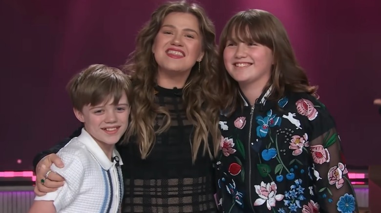 Kelly Clarkson posing with arms around son Remy and daughter River