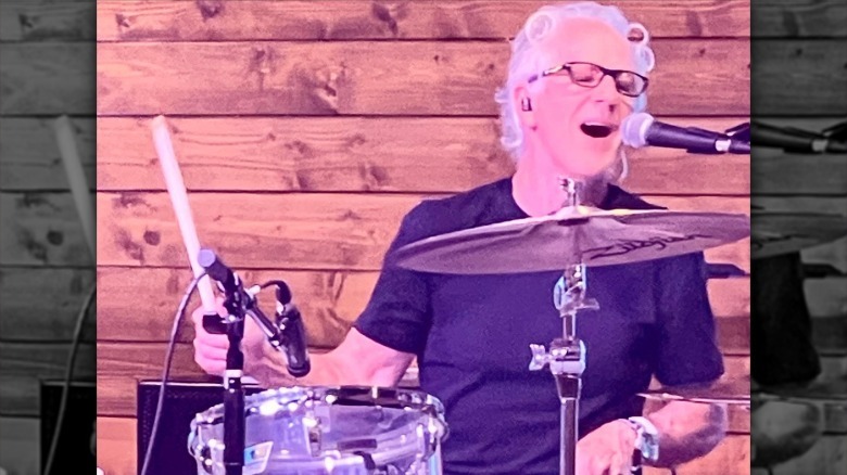 Keith Thibodeaux playing the drums and singing into a microphone
