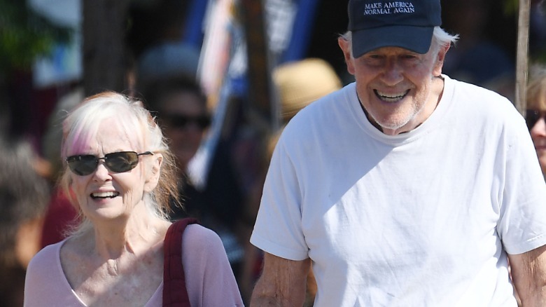 Shelley Fabares and Mike Farrell smiling and walking together outside