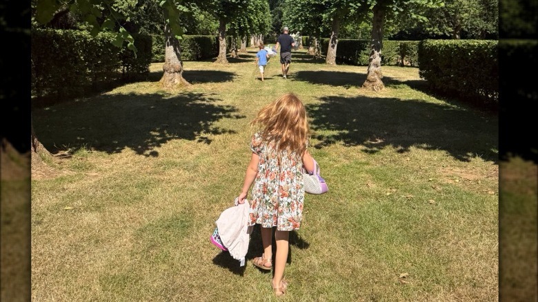Princess Lilibet walking from behind with Prince Archie and Prince Harry walking in the distance