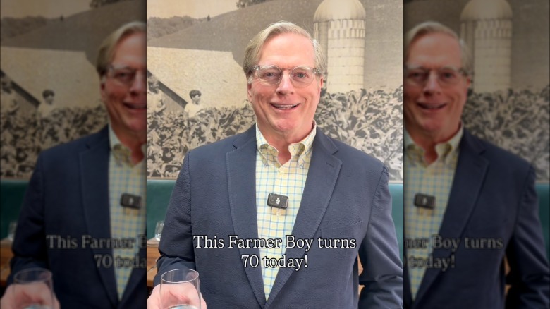 Dean Butler smiles in a suit and checkered shirt
