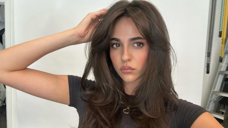 Leila Mathison holding a brown t-shirt and putting her hand on her hair