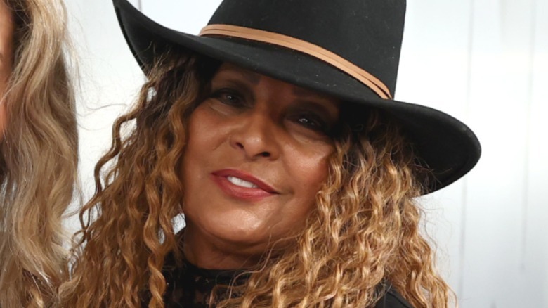 Pam Grier with light brown hair and a cowboy hat.
